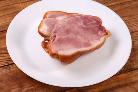 Piece of the boiled-smoked pork ham hock on a white dish on the rustic tableの写真素材