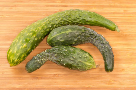 Freshly harvested green cucumbers different sizes on the cutting board, top viewの写真素材