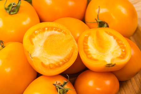 Two halves of the ripe yellow tomato lie on the same whole tomatoes, close-up in selective focusの写真素材
