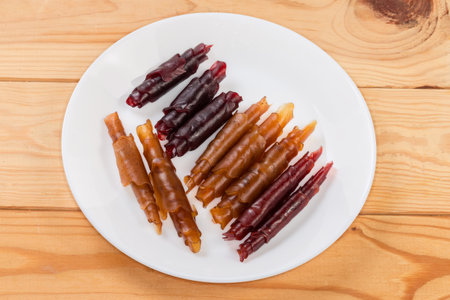 Natural thin soft flexible pastila made with apple puree drying at low temperature and rolled into tubes on the white dish on rustic tableの写真素材