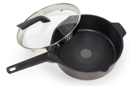 Empty deep frying pan made of cast aluminum with titanium non-stick coating with partly removed glass lid equipped with stainless steel strainer on a white backgroundの写真素材
