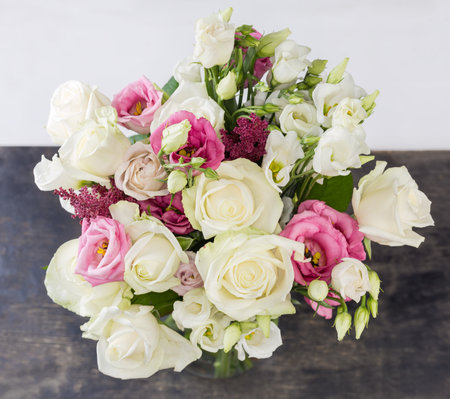 Bouquet of the white and pink roses and white eustoma in flower vase on black surface on a light background, top view in selective focusの写真素材