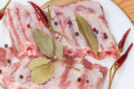 Pieces of the raw pork ribs with dried spices on the white dish, top view close-upの写真素材