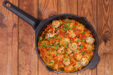 Rice meatballs stewed with red tomato sauce in the frying pan on the rustic table, top viewの写真素材