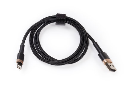 Coiled black braided cable with plugs USB Type-A and Lightning at the edges on a white backgroundの写真素材