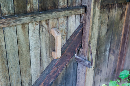Fragment of the old plank wicket darkened by time with wooden handle and antiquated wooden door latch with steel springの写真素材