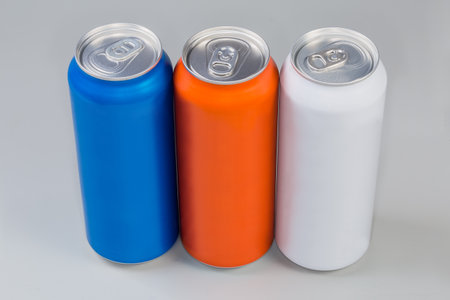 Sealed modern aluminum cans blue, white and orange colors with different beverages on a gray backgroundの写真素材