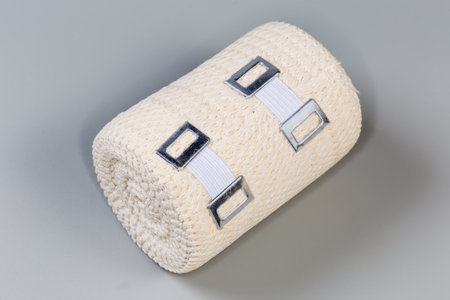 Modern woven elastic medical bandage with aluminum stretchable clips rolled into roll on a gray backgroundの写真素材