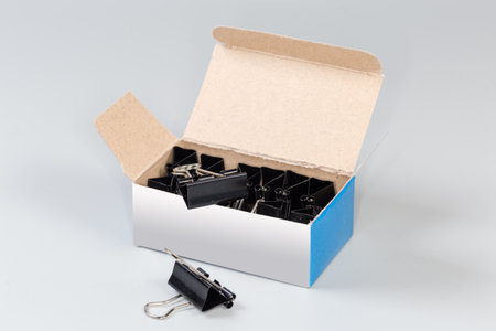 Set of the binder clips for paper packed in the open paperboard box on a gray backgroundの写真素材