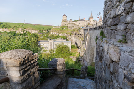 Ancient fortress of the 14-18th centuries with defensive stone wall and south side of the Castle bridge on a foreground in sunny morning, Kamianets-Podilskyi city, Ukraineのeditorial素材