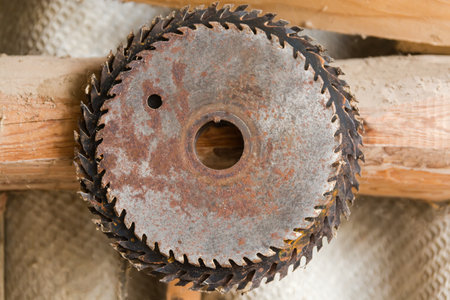 Different old partially rusty circular steel saw blades for cutting wood on a stationary electric saw machine are hanging on a wallの写真素材