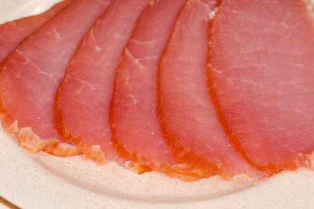 Thin slices of the dry-cured pork loin on a saucer, fragment top view close-up in selective focusの写真素材