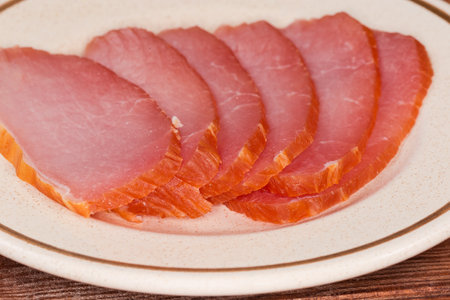Thin slices of the dry-cured pork loin on a saucer, side view close-up in selective focusの写真素材