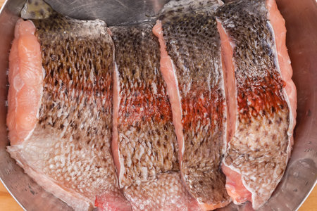 Pieces of the fresh raw chilled rainbow trout in stainless steel kitchen bowl, top view close-up in selective focusの写真素材