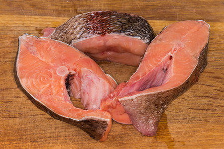 Pieces of the fresh raw chilled rainbow trout on the wooden cutting boardの写真素材