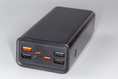 Power bank with input USB ports and several output USB and ports of other standards for portable charging of mobile equipment batteries on a gray backgroundの写真素材