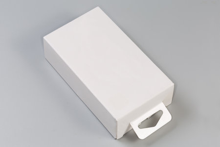 Closed rectangular hang tab packing box made with white cardboard on a gray surfaceの写真素材