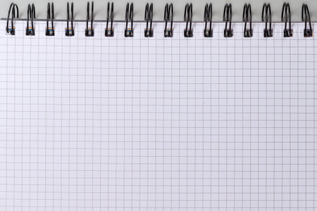 Blank sheet of squared paper of a school exercise book or paper notebook with black wire spiral binding, top viewの写真素材