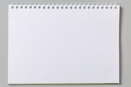 Blank white sheet of school exercise book or paper notebook with wire spiral binding on a gray background, top viewの写真素材