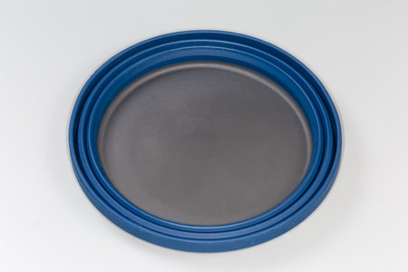 Empty tourist foldable bowl made of food-grade flexible thermosilicone in the folded state on a gray surfaceの写真素材