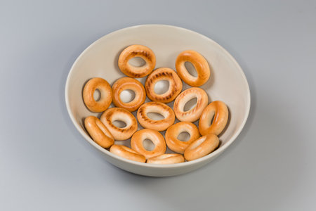 Crunchy ring shaped small cookies, so called sushki laid in one layer in bowl on a gray backgroundの写真素材