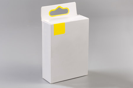 Closed rectangular hang tab packing box made with light cardboard on a gray surfaceの写真素材