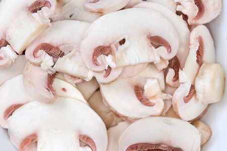Background of the fresh uncooked button mushrooms chopped into thin slices, top view close-upの写真素材
