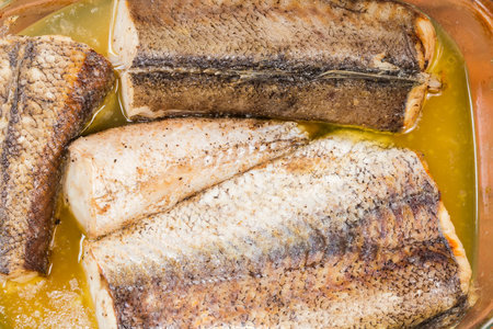 Pieces of hake baked in the glass casserole pan using oven bag for juicy healthy baking, top view...