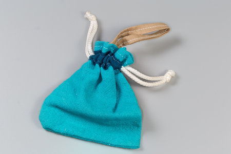 Empty small soft reusable blue fabric pouch with rope tightening closure lies on a gray surfaceの写真素材