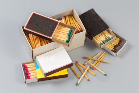 One big and several usual cardboard matchboxes with wooden household safety matches with heads of different colors on a gray surfaceの写真素材