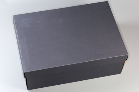 Dark gray cardboard shoes box with closed lid on a light gray background, top viewの写真素材