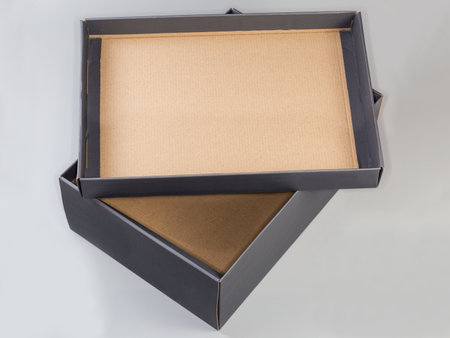Empty dark gray cardboard shoes box with removed and upside down cover from above on a light gray backgroundの写真素材