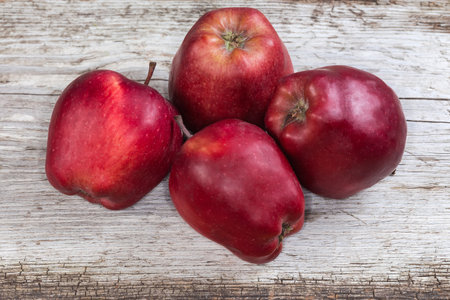 Several whole dark red apples on an old cracked wooden surfaceの写真素材