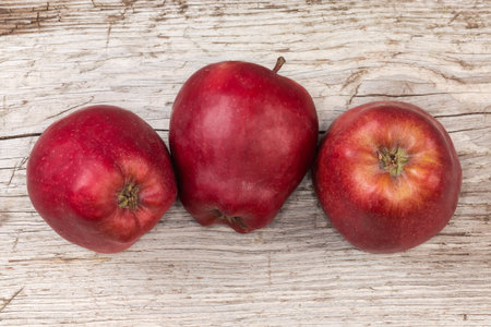 Several whole dark red apples on an old cracked wooden surface, top viewの写真素材