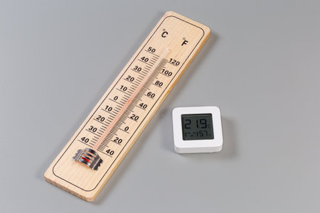 Alcohol wooden thermometer with double scale of Celsius and Fahrenheit units and digital thermometer with air humidity meter on a gray backgroundの写真素材