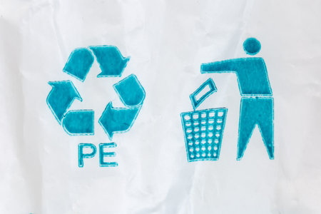 Blue universal recycling symbol with recycling code and tidy man symbol called to dispose of encouragement of packaging in the waste bin pictured on white polyethylene bagの写真素材