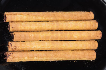 Wafer tubes with filling of chocolate cream on a black dish, top view close-upの写真素材