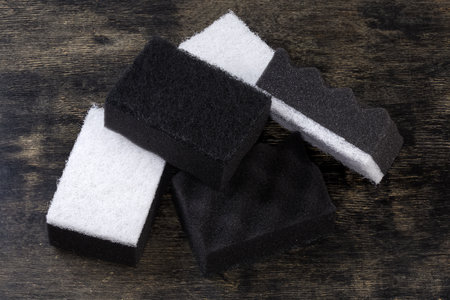 Several black and white kitchen soft synthetic cleaning sponges with hard urethane abrasive layer on a black surfaceの写真素材