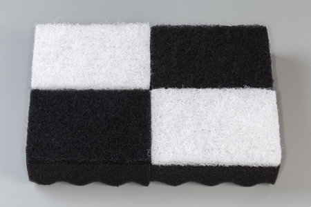 Several black and white kitchen soft synthetic cleaning sponges laid out hard urethane abrasive layer up on a gray backgroundの写真素材