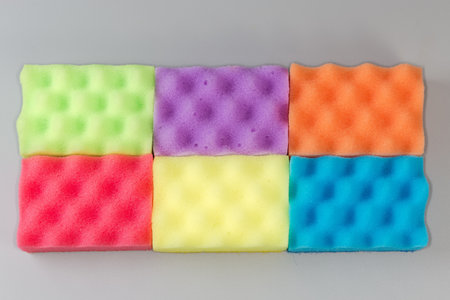 Several multi colored kitchen soft synthetic cleaning sponges laid out on a gray surfaceの写真素材