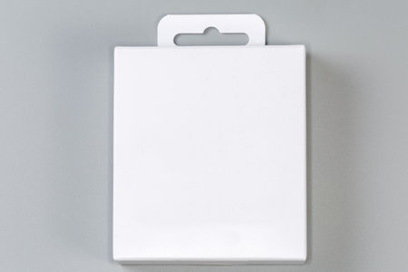 Closed rectangular hang tab packing box made with white cardboard on a gray surfaceの写真素材