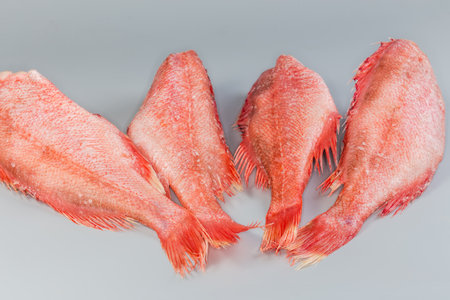 Frozen headless gutted carcasses of redfish, also known as ocean perch, covered with hoarfrost on a...