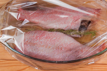 Raw ocean peppers without heads prepared for baking in the old glass baking dish placed in the plastic heatproof oven bag, close-upの写真素材