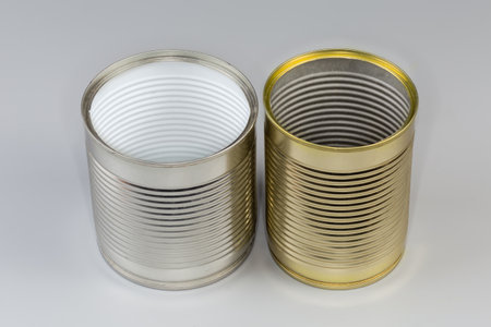 Two open empty tin cans from under a canned food, with white and yellow covering on a gray backgroundの写真素材