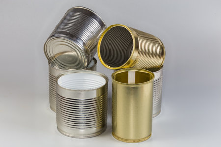 Open empty tin cans from under a canned food, different sizes with various white and yellow covering on a gray backgroundの写真素材