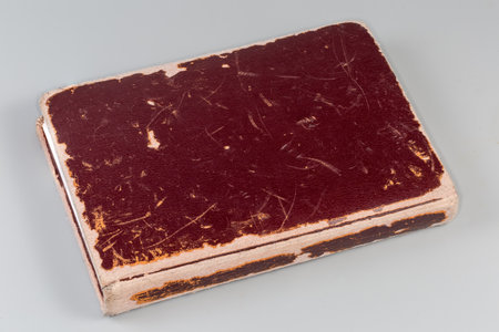 Closed old book with brown very shabby hard cover on a gray backgroundの写真素材