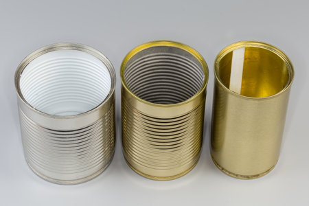 Different open empty tin cans from under a canned food, with various white and yellow covering on a gray backgroundの写真素材