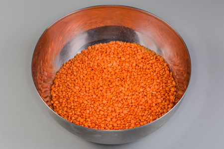 Raw whole red lentil in the stainless steel kitchen bowl on a gray backgroundの写真素材