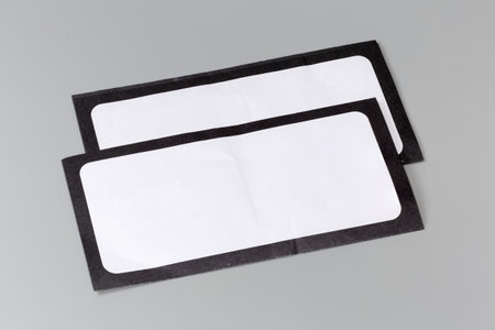Two closed blank flat rectangular mailing envelopes made with white paper with black frame around the perimeter on a gray backgroundの写真素材
