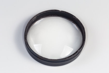 Old simple spherical lens with one convex surface and other flat surface, so-called plano-convex lens in the metal frame a gray backgroundの写真素材